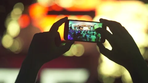 Cellphone focused while filming show and blurred background 스톡 동영상 255680888