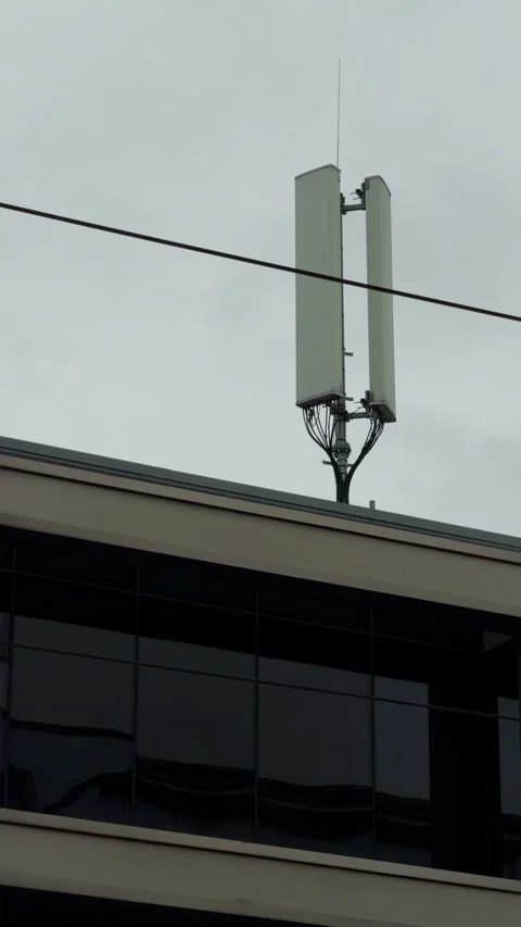 Cellular antenna mounted on modern building rooftop under overcast sky with Vídeos de archivo 345763339