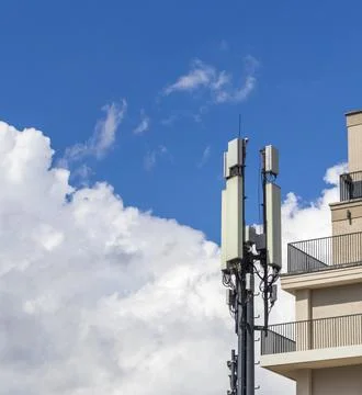 Cellular base station antennas installed next to a modern apartment buildin.. Foto stock