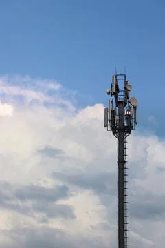 Cellular base station tower against white cumulus clouds Foto stock