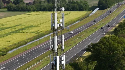 Cellular communication antenna tower next to highway traffic Stock Footage 342405591