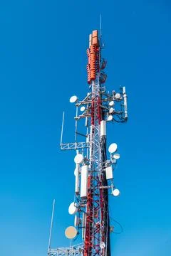 Cellular communication tower with multiple antennas and microwave dishes Stock Photos
