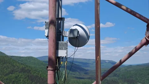 Cellular LTE antenna and microwave dish on tower with mountains Stock Footage 337952714
