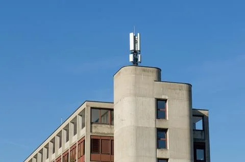 Cellular network antenna on top of modern concrete building roof against cl.. Stock Photos