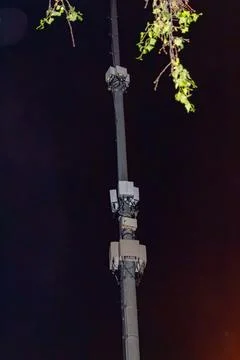 Cellular network base station antenna on a tall pole at night with green Stock Photos