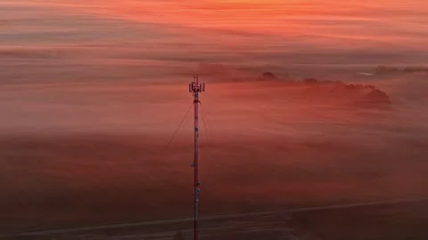 Cellular network tower standing tall above misty landscape at dawn Stock Footage 332794062