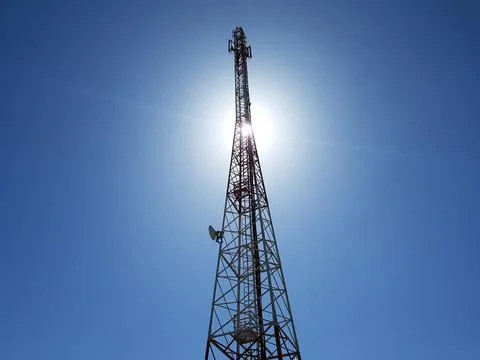 Cellular or mobile network tower against the sun in the blue sky Stock Photos