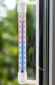 A Celsius thermometer on a window frame shows high temperatures of 43 degrees Stock Photos