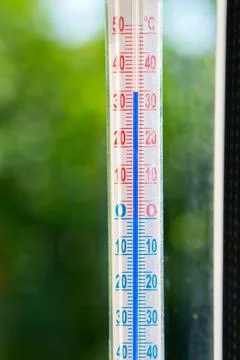 A Celsius thermometer on a window frame shows high temperatures of 35 degrees Foto stock