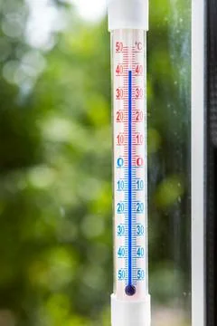 A Celsius thermometer on a window shows high temperatures of 42 degrees Stock Photos
