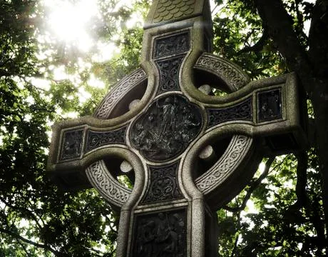 Celtic cross backlit with a background of trees. Stock Photos