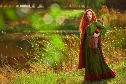 Celtic culture. A beautiful red-haired girl archer of the Middle Ages stands  Stock Photos