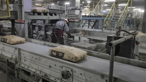 Cement Bagging Line and Worker with Shovel in a Massive Factory 4k Stock Footage 331782895