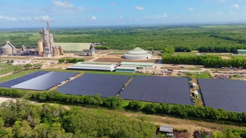 Cement factory complex with tall silos and crane stands beside four solar panel Stock Footage 340297922