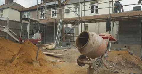Cement mixer rolling in-front of a building site Stock Footage 246378935
