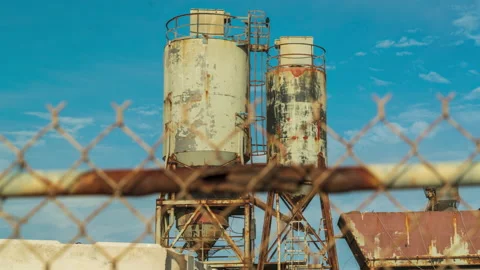 Cement mixing towers behind a chain link fence - timelapse Stock Footage 220737589