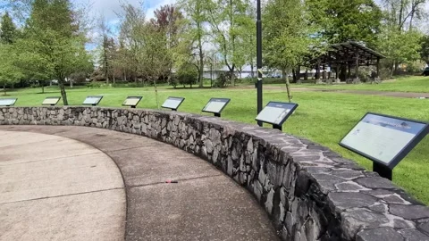 A cement path curves beside a rock wall displaying educational signs Stock Footage 342365071