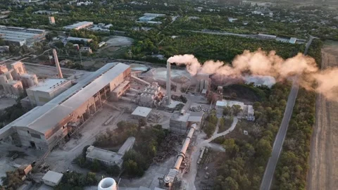 Cement plant exhaust stack with visible plume beside rotary drum dryers in drone Stock Footage 346924292