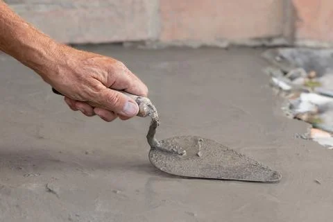 Cementation of a garden path.A man manually spreads the cement mixture with a Stock Photos