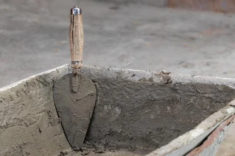 Cementation of a garden path.A man manually spreads the cement mixture with a Stock Photos