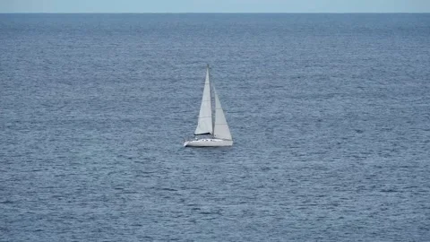In the center of the frame, from left to right, a white sailing yacht sails past Stock Footage 303245801