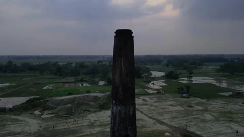 Center framed aerial view of brick kiln chimney with setting red sun at moo.. Video stock 345328899