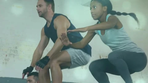Center leading upward drive, three team members doing jump squats in gym for Stock Footage 323372170