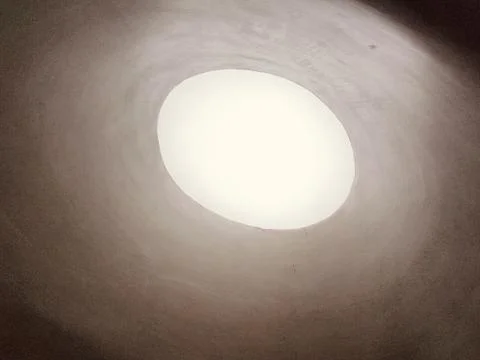 In the center of an oval opening in the white ceiling, light shines down fr.. Stock Photos