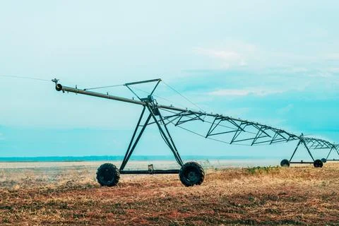 Center pivot irrigation machine spans a dry farmland field at dusk, illustr.. Stock Photos
