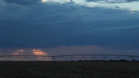 Center pivot operating at sundown as rain clouds were coming on, 4K. Stock Footage 241673335