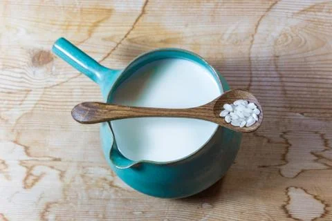 Centered view of blue green ceramic pitcher bowl of rice milk, wooden spoon Stock Photos