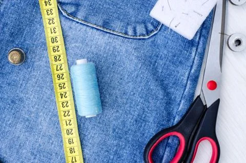 A centimeter, thread, pins and a thimble, and large scissors lie on things Stock Photos