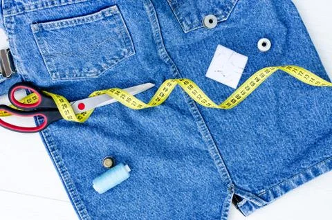 A centimeter, thread, pins and a thimble, and large scissors lie on things Stock Photos