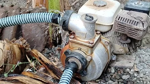 Central Java Indonesia 27 July 2026: Portable gasoline-powered water pump connec Stock Footage 340898288