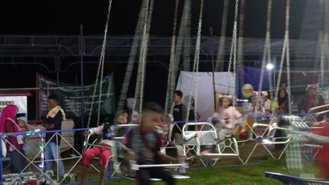 Central Java, Indonesia. April 15,2024: Children ride the swing rides Stock Footage 274828508