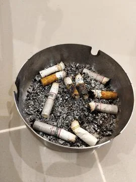 CENTRAL JAVA, INDONESIA - AUG 14, 2026: A stainless steel ashtray filled with ci 스톡 사진