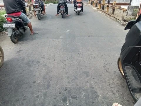 Central Java, Indonesia August 22 2024: Motorbike riders stopped at the railway Фото