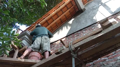 Central Java, Indonesia, July 11, 2025: People are plastering cement on a buildi Stock Footage 313578355
