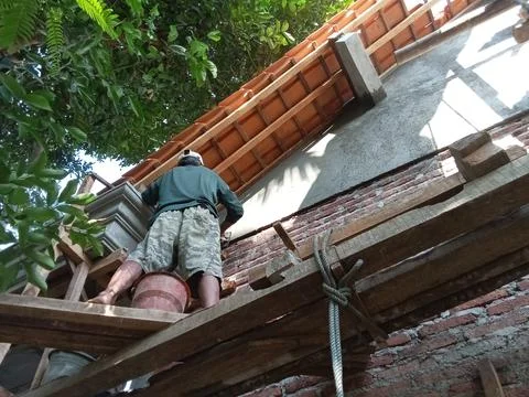 Central Java, Indonesia, July 11, 2025: People are plastering cement on a buildi Фото