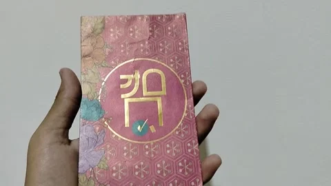 Central Java, Indonesia, March 24, 2026: A person holds a red envelope Stock Footage 332159516