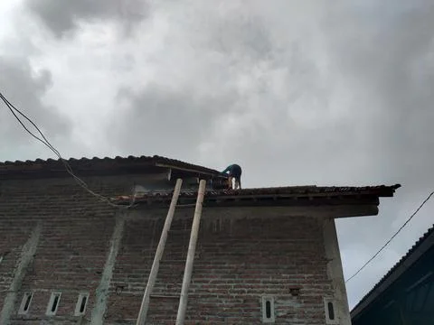 CENTRAL JAVA, INDONESIA - OCT 30, 2026: A brave man climbs a high roof using a t Stock-Fotos