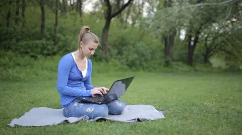 In the central park sitting on the grass young girl working on laptop Stock Footage 62844900