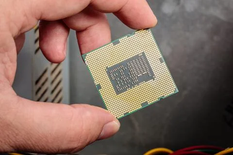 Central processing unit in a man's hand next to a computer Foto stock