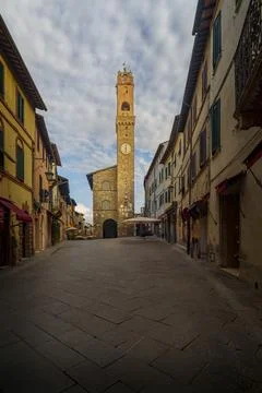 Central square with medieval clock tower, stone pavement, and Tuscan townhous Stock Photos