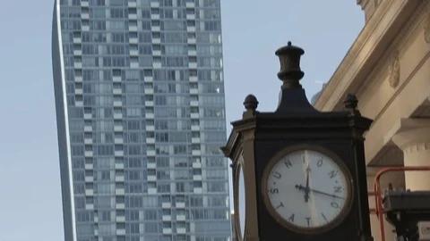 Century old clock train station clock with tilt to modern day skyscraper Stock Footage 73966089