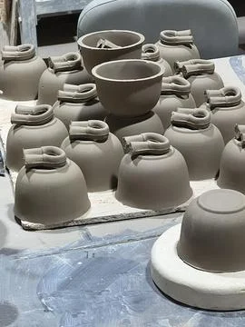 Ceramic artisans create clay vessels in a workshop, with multiple pieces in v Stock Photos