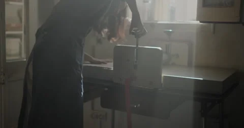 Ceramic artist using a slab roller in a sunlit studio. The misty atmosphere adds Stock Footage 302554446