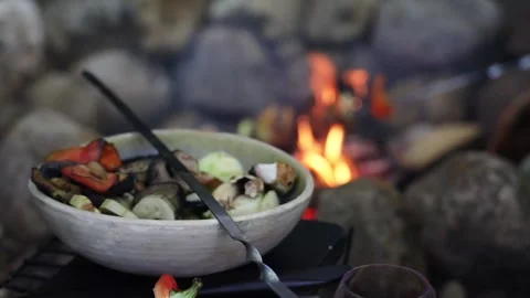 A ceramic bowl of vegetables stands by the fire Stock Footage 277567648
