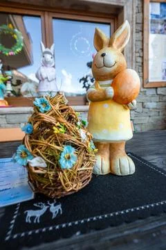 Ceramic bunny with orange Easter egg on rustic table in cafe setting Stock Photos