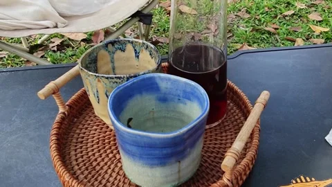 Ceramic coffee cups and a glass server on a rattan tray outdoors. Stock Footage 339780422